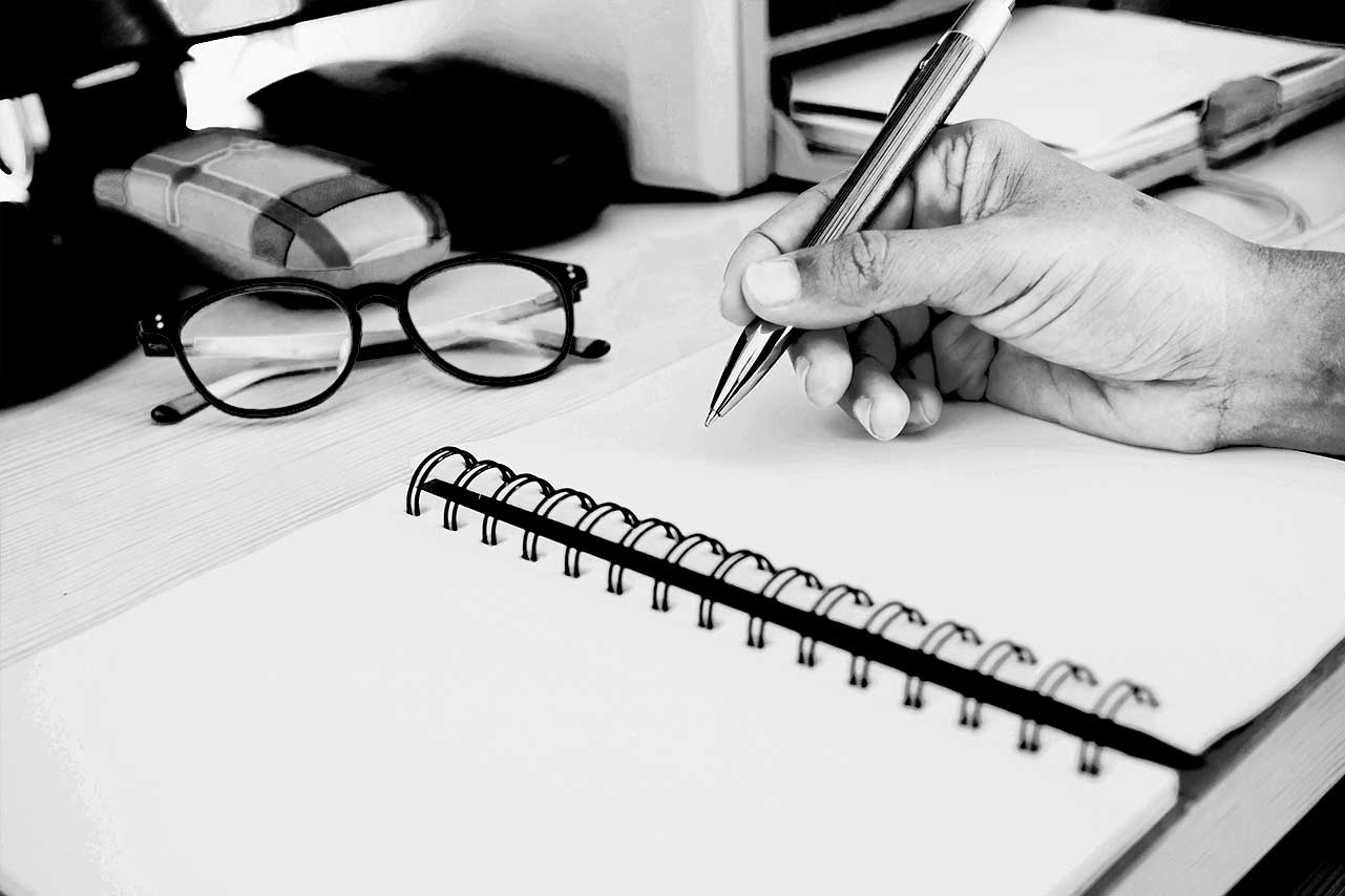 Main écrivant dans un carnet, symbolisant la planification d'une stratégie digitale réussie.