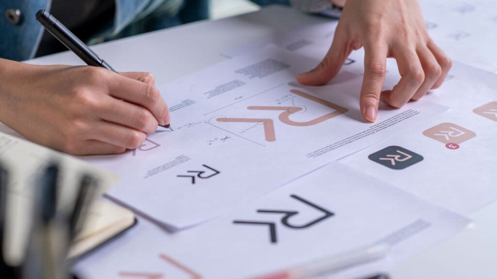 Designer créant un logo professionnel sur papier – importance du logo dans la stratégie de marque